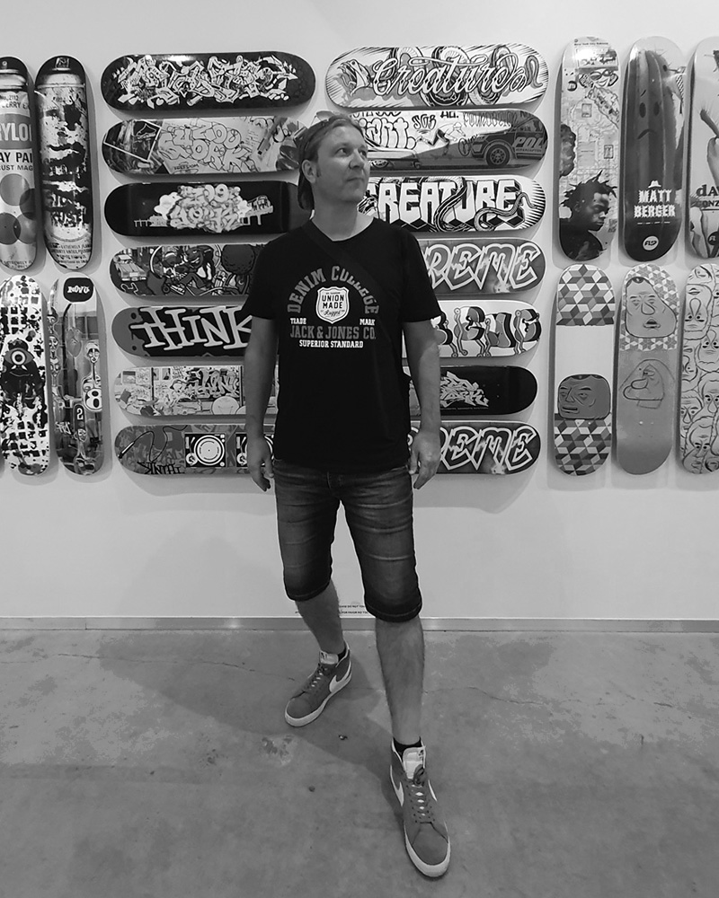 Black and white portrait of Fred, graphic designer and Popterror co-founder, in front of a skateboard wall