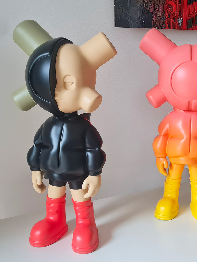 Deux sculptures EQSO grand format : l’une avec une capuche noire et des bottes rouges, l’autre en dégradé rose, orange et jaune